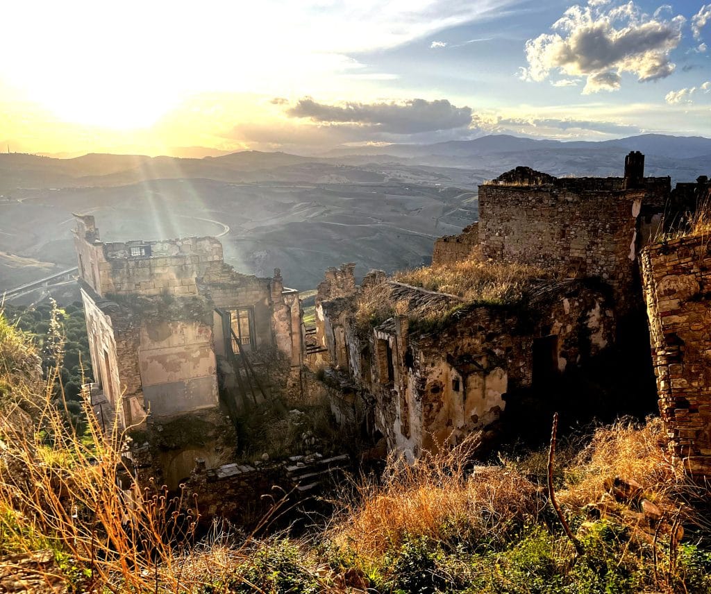Ghost town of Craco ruins at sunset with Calanchi badlands in the background