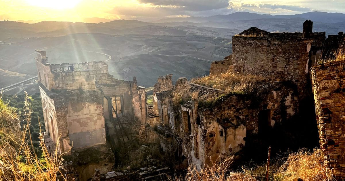 Ghost town of Craco ruins at sunset with Calanchi badlands in the background
