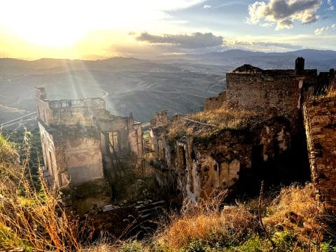 Ghost town of Craco ruins at sunset with Calanchi badlands in the background