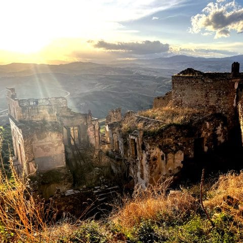 Ghost town of Craco ruins at sunset with Calanchi badlands in the background