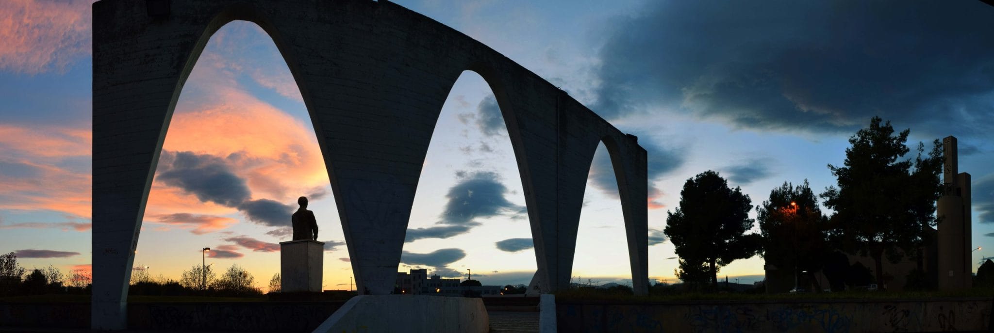 Modernist concrete arches of the Herakleia monument in Policoro at sunset