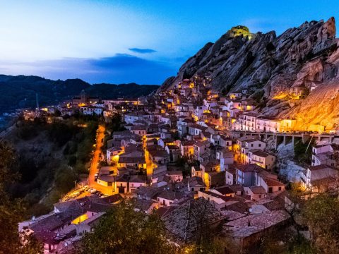 The village of Castelmezzano at dusk with illuminated houses against the Lucanian Dolomites sandstone cliffs