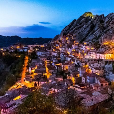 The village of Castelmezzano at dusk with illuminated houses against the Lucanian Dolomites sandstone cliffs