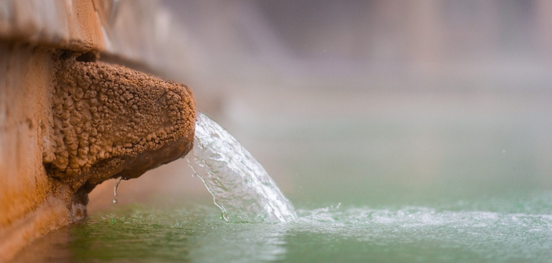 Thermal water flowing from a stone spout into the pool at Hotel La Posta, Bagno Vignoni