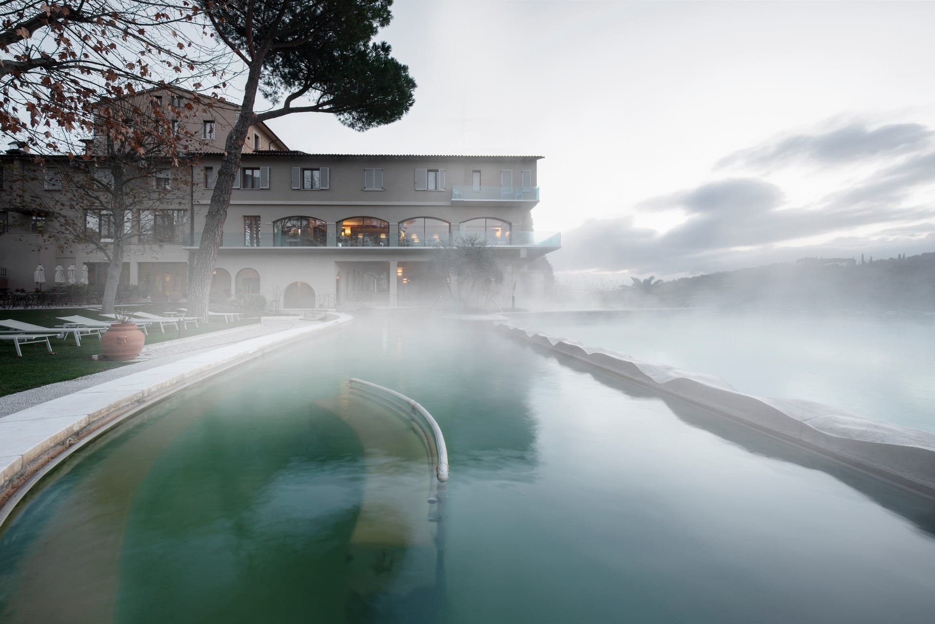 The thermal pool at Hotel La Posta with steam rising and the hotel building beyond