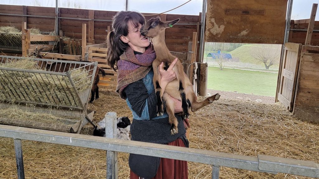 Valentina Gadotti holding a goat inside a barn at Podere le Fornaci farm