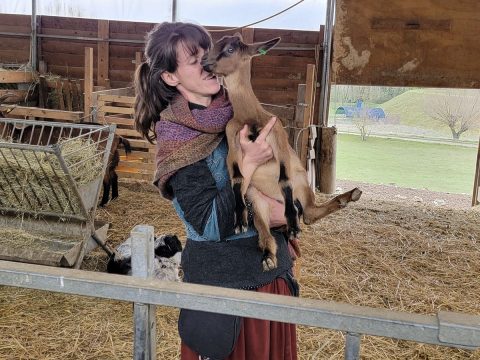 Valentina Gadotti holding a goat inside a barn at Podere le Fornaci farm