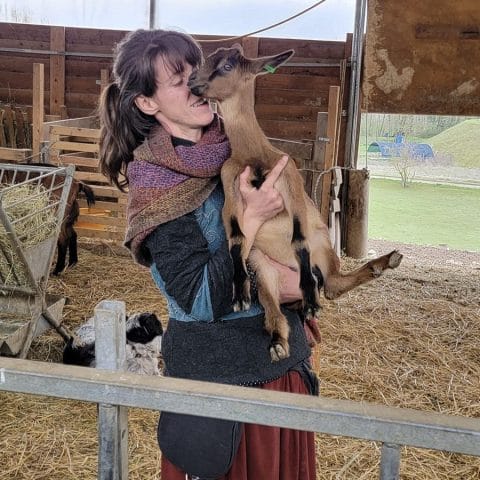 Valentina Gadotti holding a goat inside a barn at Podere le Fornaci farm