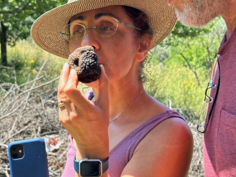Numenvia guest smelling a truffle during truffle hunting at Poggio a Campoli with another guest nearby