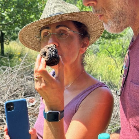 Numenvia guest smelling a truffle during truffle hunting at Poggio a Campoli with another guest nearby