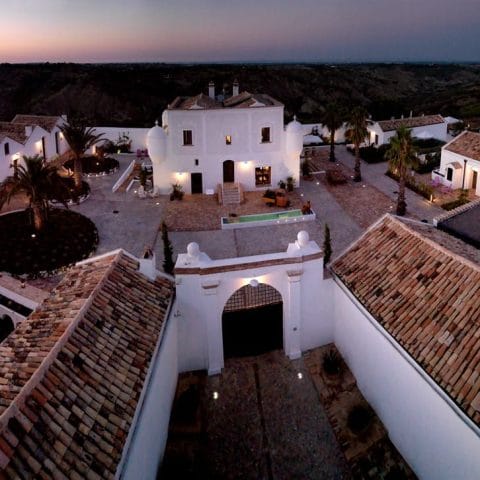 Aerial view of Torre Fiore boutique hotel at dusk, white buildings around a courtyard in Pisticci