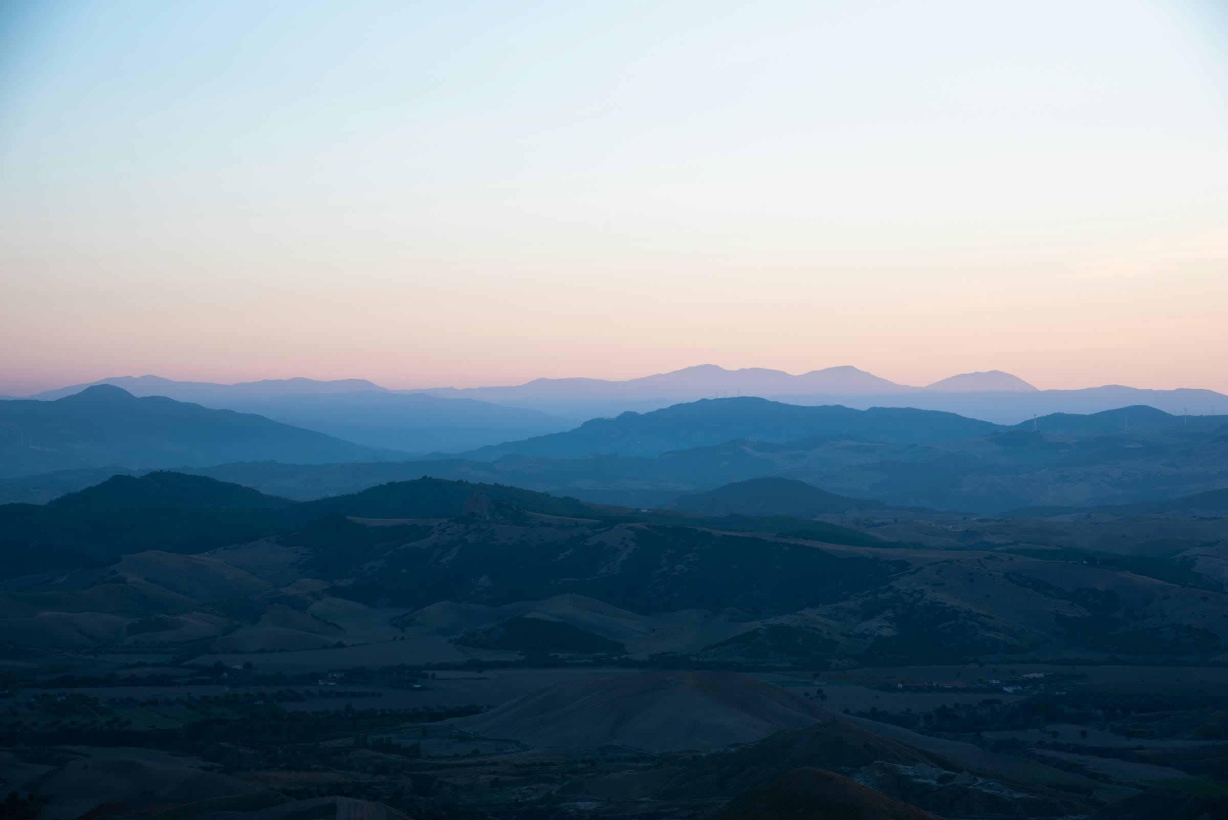 Layered blue mountain ridges of Basilicata fading into a pink dusk sky