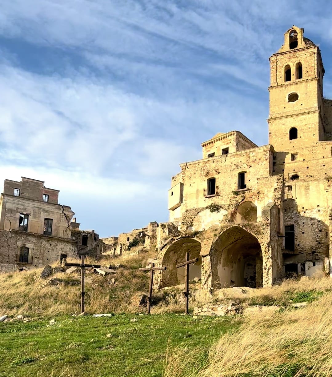 The abandoned stone ruins and bell tower of the Craco ghost town on a grassy ridge
