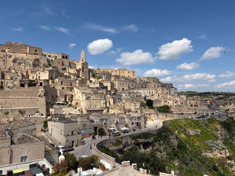 The ancient Sassi of Matera under a blue sky, stone houses tumbling toward the canyon