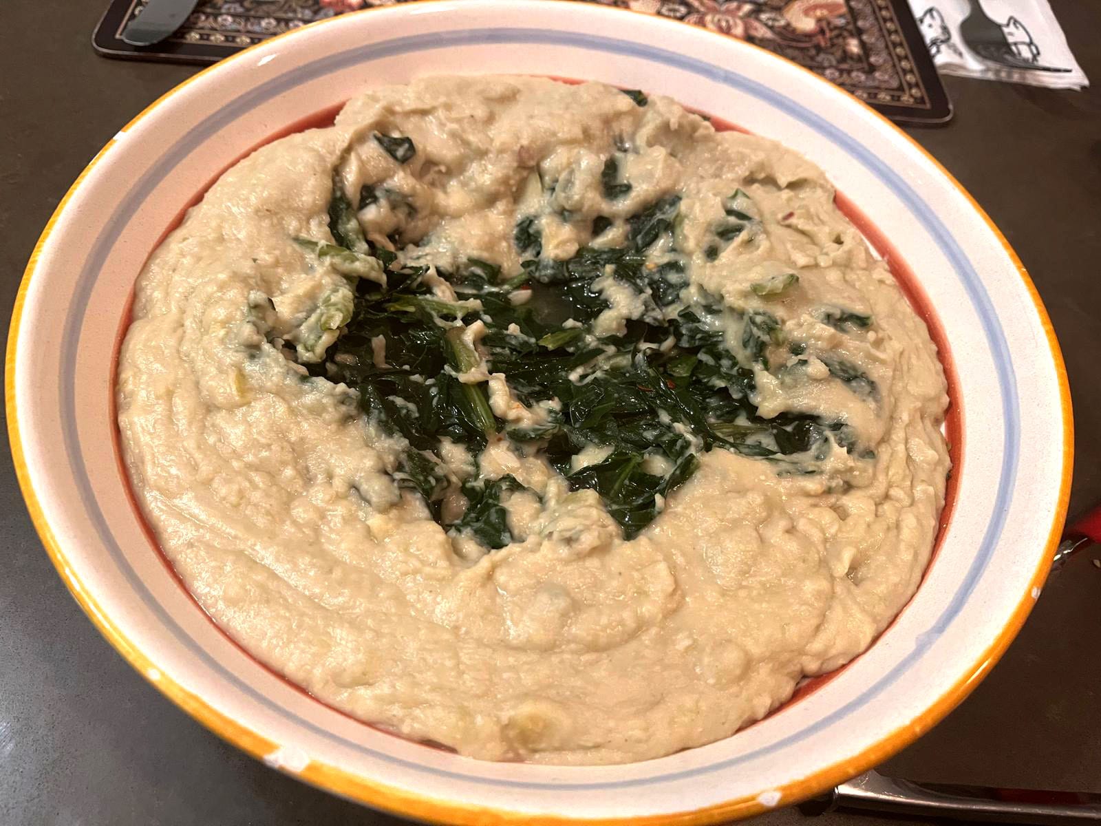 A bowl of dandelion greens over mashed fava beans