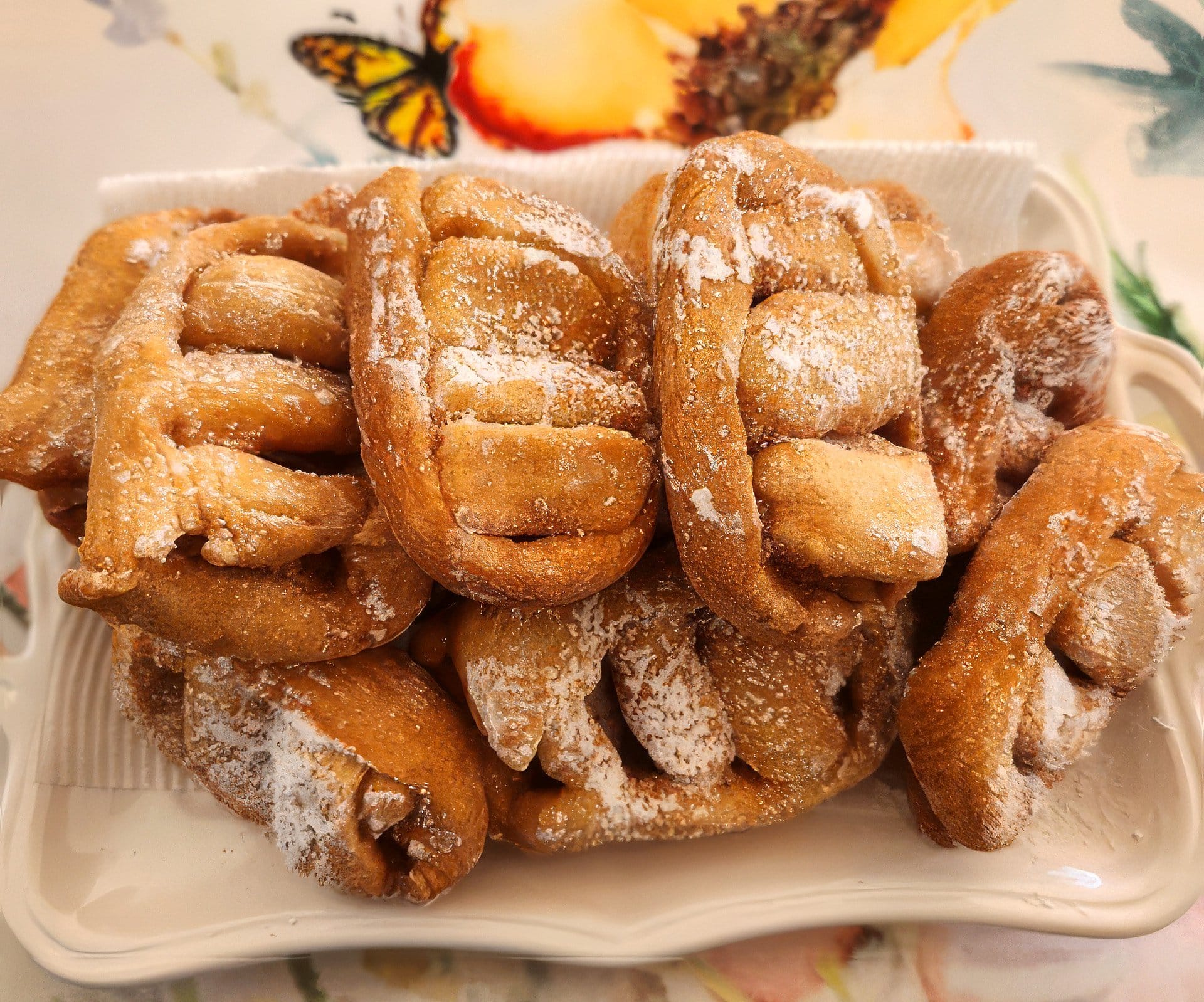 Elisa’s nacatoli: fried pastries with a basket-weave pattern, dusted with icing sugar, on a white dish.